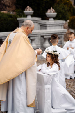 dziewczynka przyjmująca od biskupa pierwszą komunię świętą