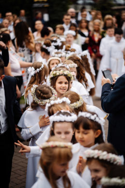 dzieci w dniu pierwszej komunii świętej czekają w szeregu przed kościołem