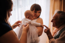 babcia dotyka placem dłoń dziecka w dniu chrztu